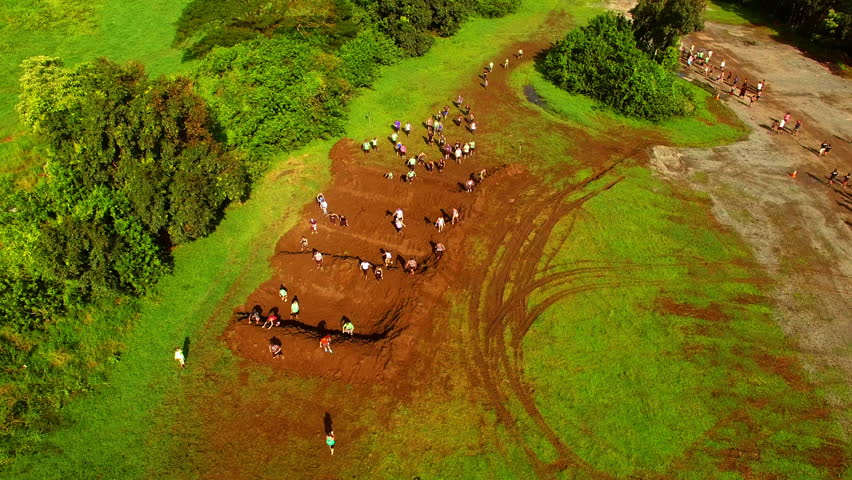 Aerial Shot Of Athletes Running On Mud Obstacle During Race, Drone Flying Backward Over Dirt Road - Oahu, Hawaii