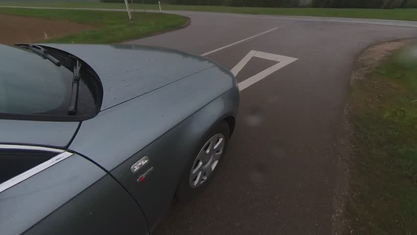 A Car Crossing an Intersection on a Rainy Day.