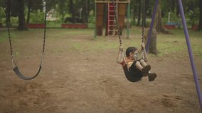 Indian boy sitting on swing in city park. concept of loneliness but happy.