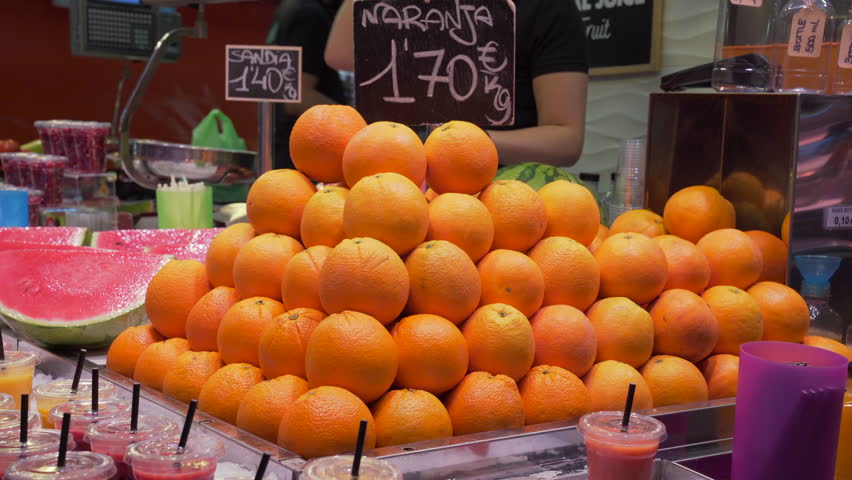 Market stall with stacked oranges, watermelons and prepared fruit juice in the Central Market (Mercado Central) of Valencia, Spain.