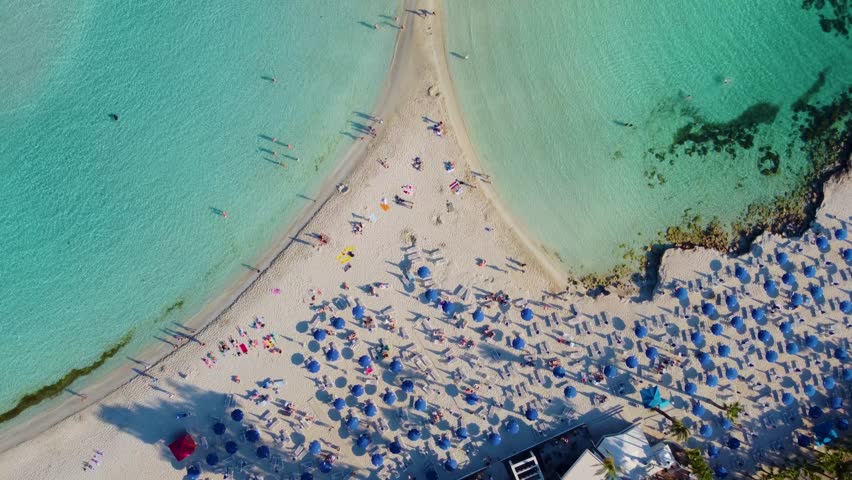 Aerial View Of Tourists In Nissi Beach And Sand Bar To Island During Summer In Ayia Napa, Cyprus. - overhead Royalty-Free Stock Footage #1104672453