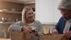 Adults happy family couple middle-aged senior man woman unpacking shopping bags purchases food delivery order products wife showing jam husband show thumb up unpack goods at kitchen healthy meal diet - Powered by Shutterstock - Get 15% off with code: PIKWIZARD15