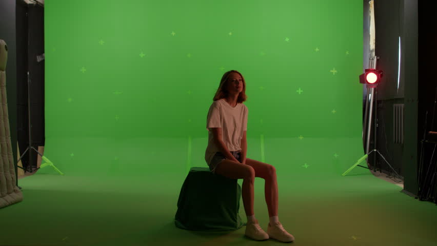 Silhouette young caucasian woman sitting on the top of a mountain or roof watching the sunset with beautiful landscape on Green screen background, chroma key.