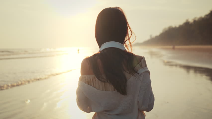 Relax asian woman wearing headphones walking in the sea beach at golden sunset - Female tourist listening to music on summer vacation Royalty-Free Stock Footage #1104683367