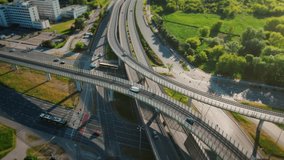 Busy multi-level interchange in the sunrise sunshine. Aerial view of the junction and moving cars. Transportation infrastructure concept. High quality 4k footage