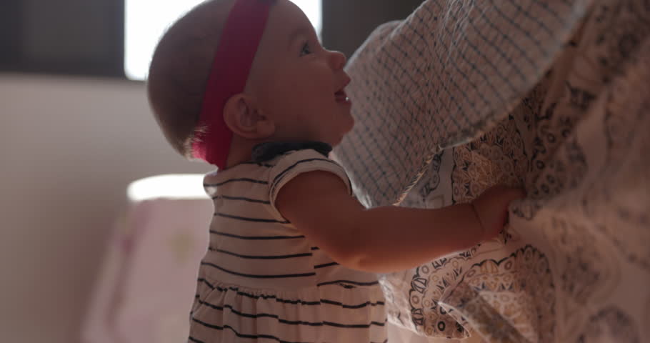 Young baby girl standing up for first time by holding onto parents bed - excited cute learning | Shutterstock HD Video #1104692381