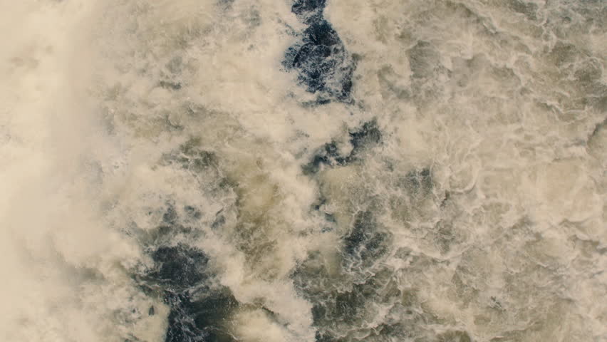 Aerial view of white water rushing down river and waterfall in slow motion 40fps