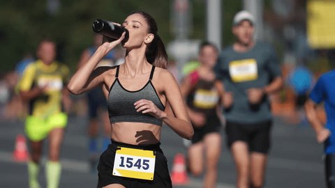 Woman athlete drink water bottle. Thirsty people run long distance. Girl sport runner work out. Adult person train public park. Thirst jogger take break. Jog city arena. Sprinter drinks fresh shake. Arkivvideo