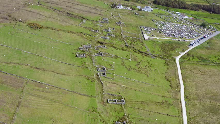 Tilt down aerial reveals historic archeological rock wall ruins of old abandoned village at slievemore, ireland