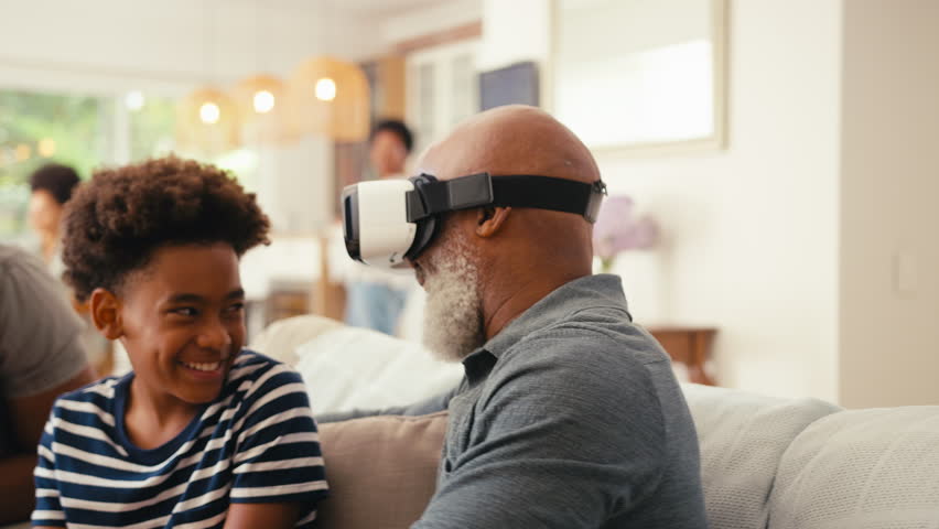 Grandfather wearing VR headset as multi-generation male family sitting on sofa at home together - shot in slow motion | Shutterstock HD Video #1104705491