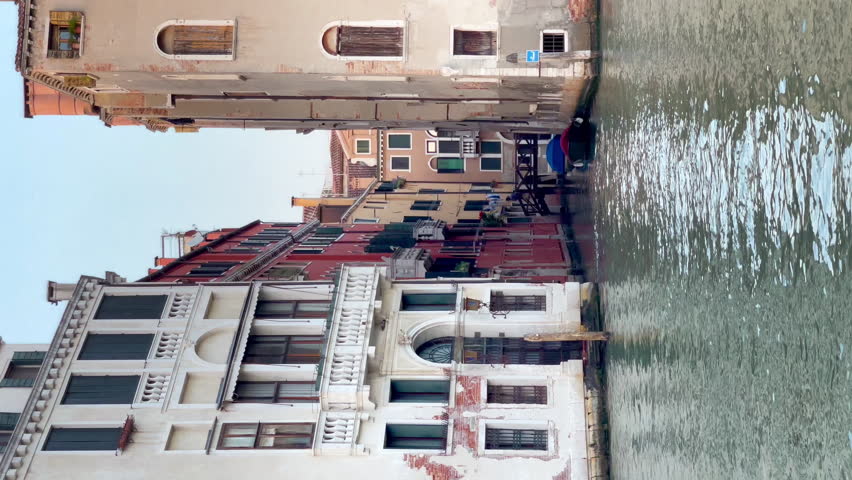 4K video of a narrow Venetian streets with green waves Grand Canal view near Rialto Bridge, Adriatic Mediterranean sea, Venice, Veneto region, Italy.