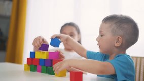 children in kindergarten play with blocks on table by the window. education development children game concept. children play with blocks at home rejoice having. children play together at fun home - Powered by Shutterstock - Get 15% off with code: PIKWIZARD15