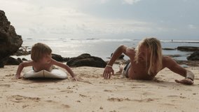Touching slow motion shots, loving father teaches his little son to swim, paddle properly with hands and ride surfboard. Young man dad teaches his young son surfing. Father and son surfers on beach. - Powered by Shutterstock - Get 15% off with code: PIKWIZARD15