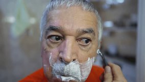 Older man shaving beard in front of bathroom mirror, old age domestic lifestyle morning ritual, close-up face - Powered by Shutterstock - Get 15% off with code: PIKWIZARD15
