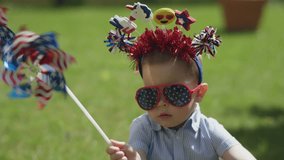 USA independence day concept little boy kid in funny american hairband blowing red, white and blue windmill, sitting on green grass sunny day outdoors. happy american lifestyle family celebration - Powered by Shutterstock - Get 15% off with code: PIKWIZARD15