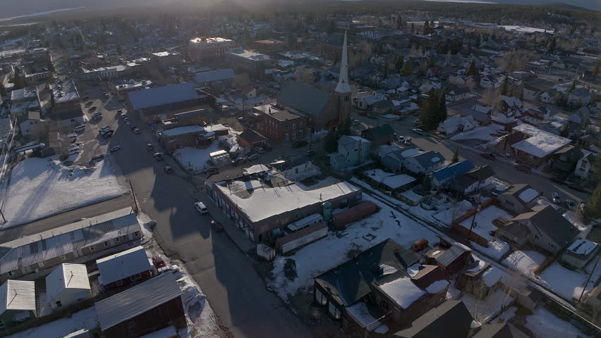 Leadville Aerial cinematic drone Colorado historic downtown winter spring snowy street buildings cathedral catholic late afternoon early evening blue sky bright sunshine forward pan up reveal movement