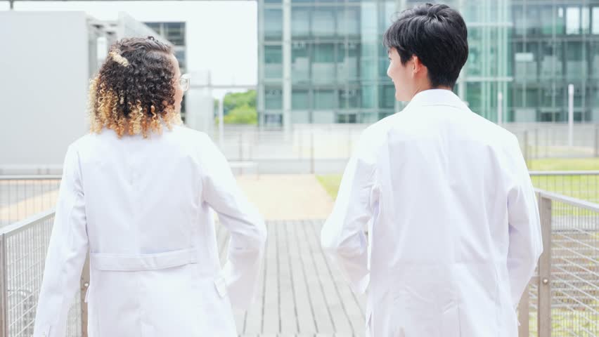 A multinational group wearing a white coat and walking through a facility.