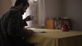 Wide shot- Middle-aged white man reading newspaper and sipping tea in room.Rear - Powered by Shutterstock - Get 15% off with code: PIKWIZARD15