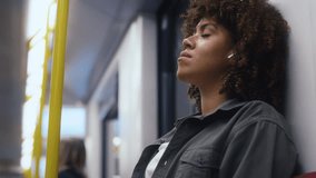 Young afro woman traveling by underground and relaxing with earphones. Shot with RED helium camera in 8K. 