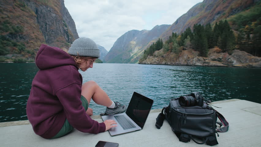 Social media content creator, young millennial photographer work remotely on laptop in epic Scandinavian scenery. Video blogger or influencer, travel around Norway and work on projects Royalty-Free Stock Footage #1104748769