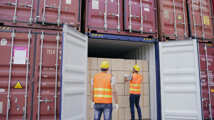Foreman and a worker help opening containers together and lifting the box  while female assistant check stock by computer at the transport warehouse. Cargo container and Transport Logistic concept