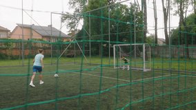 The female coach is training a young boy football player. The woman takes a free kick towards the goal, and the young goalkeeper, successfully blocks the shot. The shot is taken through a barrier net. - Powered by Shutterstock - Get 15% off with code: PIKWIZARD15