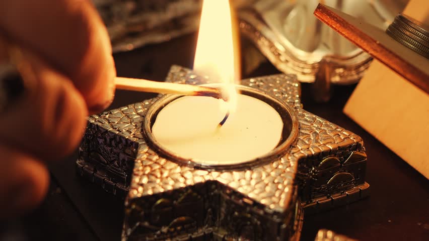 A woman's hand lights candles on the eve of Shabbat in candlesticks in the shape of a star of David. Medium plan Royalty-Free Stock Footage #1104768019