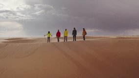 Group of five young hikers with backpacks stands at sandy dune at sunset time - Powered by Shutterstock - Get 15% off with code: PIKWIZARD15