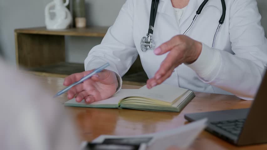 Close-up of a cropped shot of a family doctor, a medical worker sitting at a table with a patient and talking about upcoming treatment or the results of tests or examinations. Medical insurance. 4k | Shutterstock HD Video #1104770071