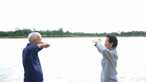 Video of Asian Senior Elderly couple Practice Taichi, Qi Gong exercise outdoor next to the lake