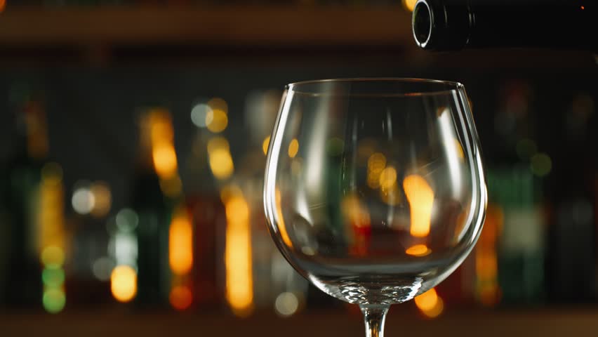 Super Slow Motion Shot of Pouring Red Wine into Glass Before Bar at 1000fps.