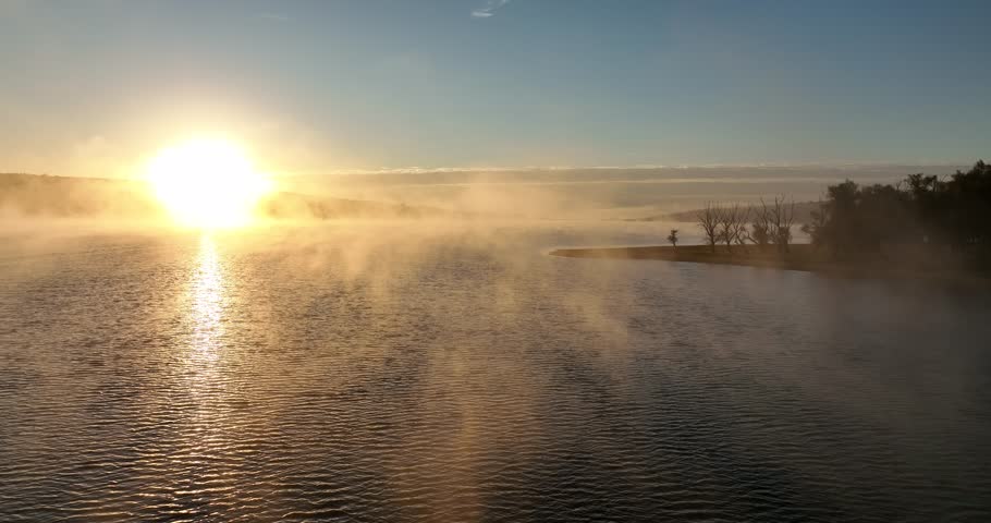Fog on a lake. Aerial drone view over sunset lake. Peaceful reflection of the beautiful sunset lake. Landscape during the evening, greenery