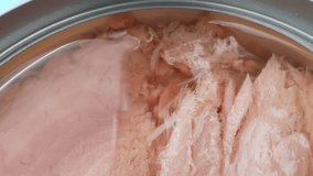 Dive into a captivating macro video of canned tuna, unveiling its exquisite texture, shimmering hues, and succulent flakes, a tantalizing feast for the eyes.
