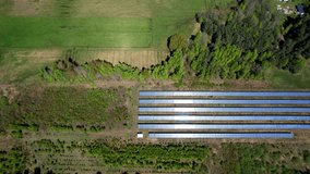 Drone clip moving right to left over countryside and solar farm with photovoltaics