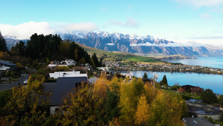 Beautiful queenstown view. Drone shot of roads and buildings next to the water. Cozy downtown of Queenstown in moody cloudy weather, New Zealand. mountains in the background Royalty-Free Stock Footage #1104786427