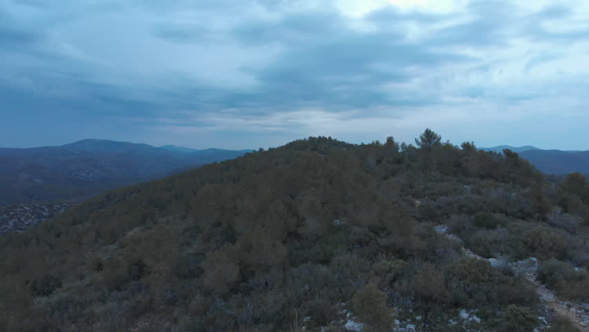 Hilltop watchtower captured in an aerial drone shot during a dramatic overcast dawn