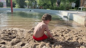 Little boy toddler playing with sand on beach ocean sea and building sand castle digging a hole in the sand. Slow motion. High quality 4k footage
