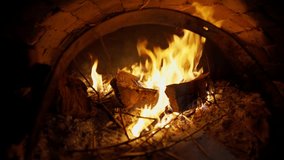 A brick pizza oven with fire and flame. Firewood burning in the wood-fired oven with open door. A traditional oven for cooking and baking pizza. Warm cozy fire in a fireplace. Video footage 4k 25FPS