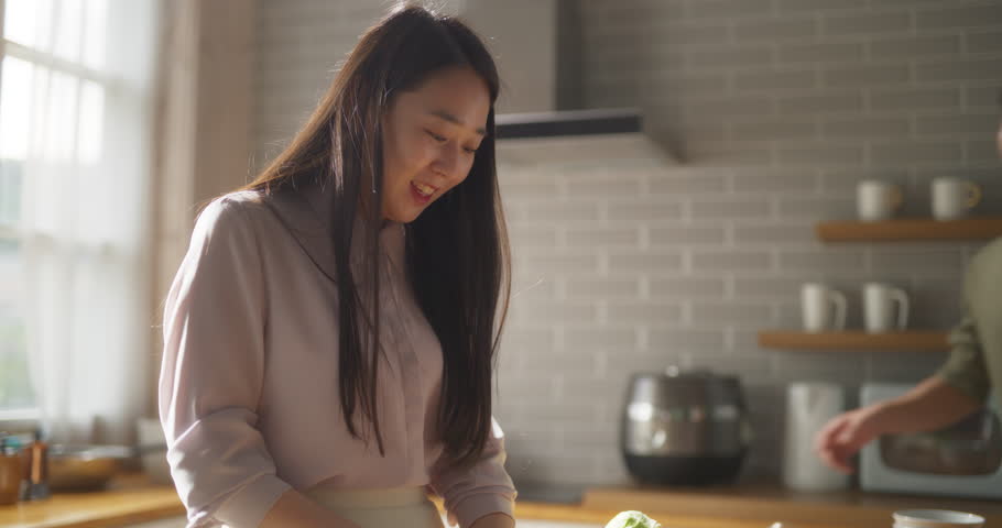 Portrait of a South Korean Young Couple Cooking at Home. Loving Boyfriend and Girlfriend Preparing Dinner in the Kitchen, Having a Funny Conversation While Cooking Delicious Food Royalty-Free Stock Footage #1104788067
