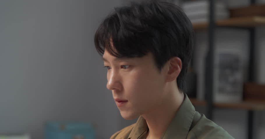 Portrait of a Young and Handsome South Korean Professional Working on Laptop Computer Behind a Desk at His Cozy Stylish Office. Asian Specialist Dealing with Documents, Researching Data for a Project