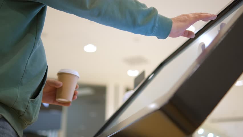 Man using touchscreen terminal in mall. Detail view outstretched male hand touching modern big timetable or info screen in interior 4K