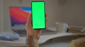 Handheld Camera: Point of View of Man at Modern Room Sitting on a Chair Using Phone With Green Mock-up Screen Chroma Key Surfing Internet Watching Content Videos Blogs