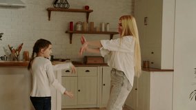 Mom and daughter dancing in the kitchen to cheerful music. The concept of a good fun morning. spend time together