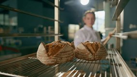 female baker takes out freshly baked fresh bread from the oven and puts it on the shelf in kitchen of the bakery Culinary profession - Powered by Shutterstock - Get 15% off with code: PIKWIZARD15