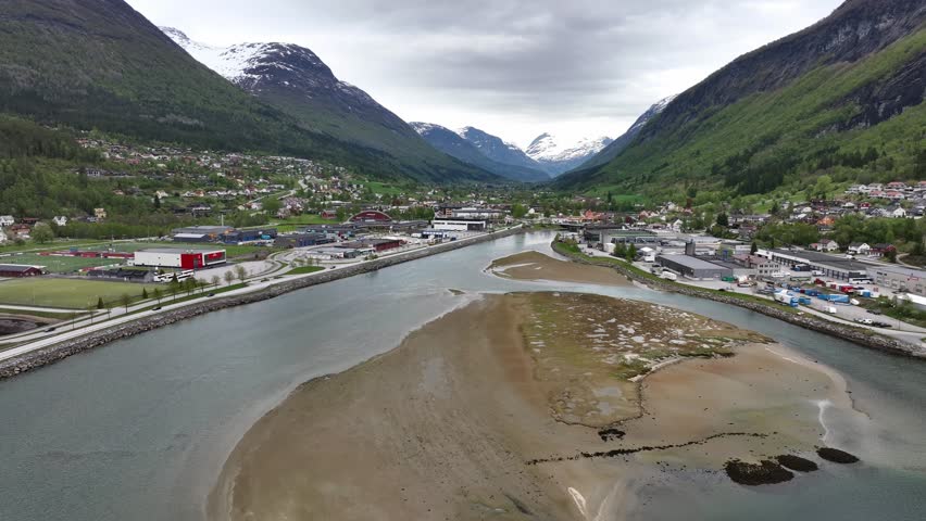 Village of Stryn Norway - Springtime aerial above Stryn river with lush green hillsides and snow capped mountainsides - Norway Nordfjord