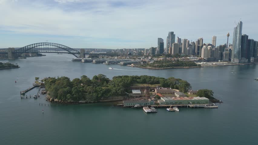 Aerial pull back shot over Goat Island, Port Jacson in Sydney, New South Wales, Australia. Showing its iconic Sydney Harbour, skyline, landmarks, and city CBD central business disctrict.