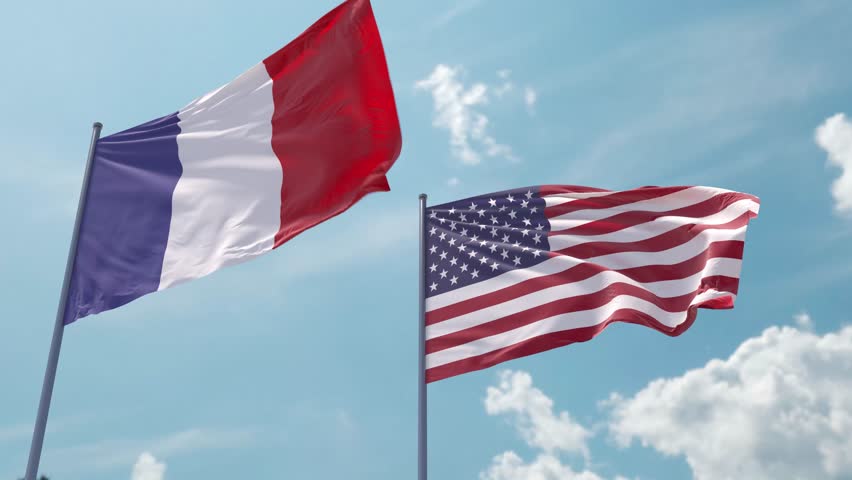 France flag and the USA flag on a flagpole realistic wave on strong wind in blue sky. French Republic and The United States of America Royalty-Free Stock Footage #1104811353