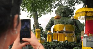 Slow motion shot of an influencer making a video of a big baby statue monument on her bali trip through indonesia for social media