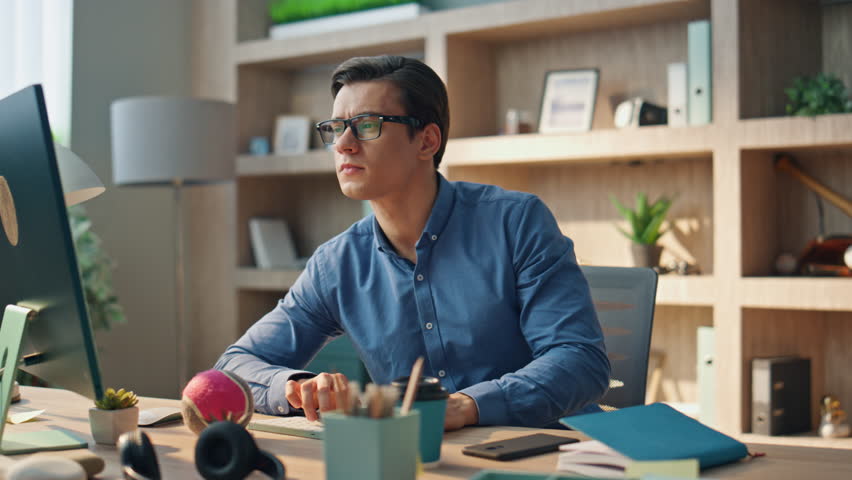 Focused creator typing computer keyboard at office interior closeup. Serious web designer sitting at pc monitor work place. Eyeglasses man pushing keyboard buttons working at cabinet room alone - Powered by Shutterstock - Get 15% off with code: PIKWIZARD15