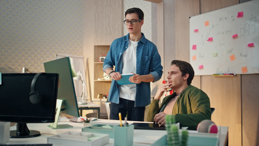 Inspired creators pointing computer screen at office. Eyeglasses creative businessman gesturing hand talking to colleague. Two smiling partners working pc analysing project. Team planning strategy Royalty-Free Stock Footage #1104814469